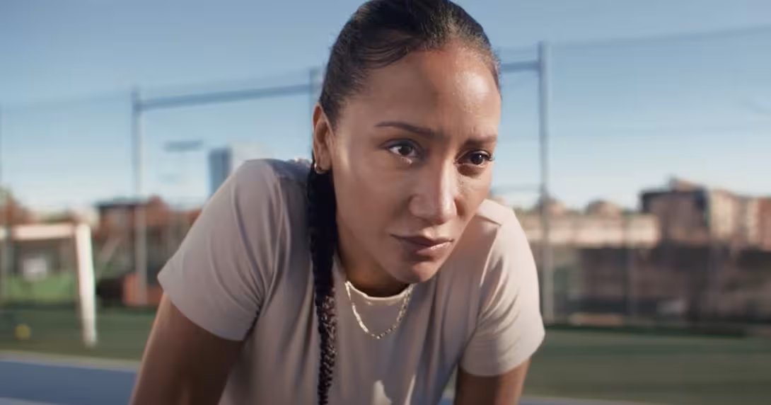 A woman wears a beige shirt and lines up on a field