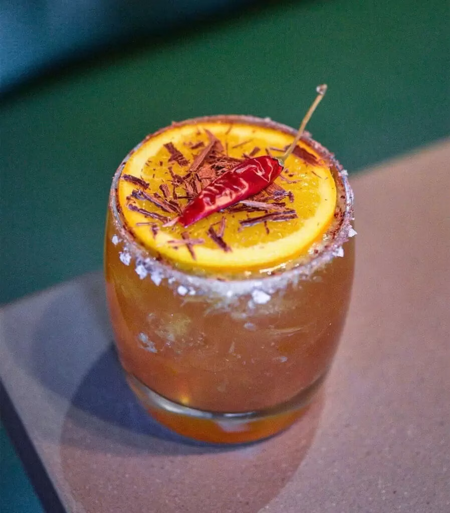 A margarita in a low cocktail glass garnished with orange and cinnamon