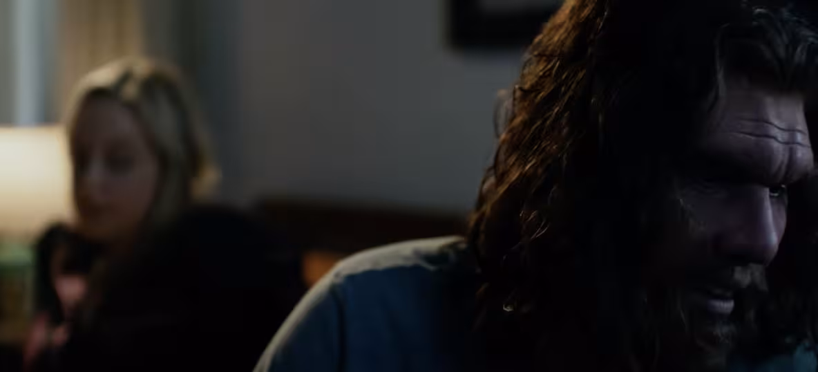 GEICO Caveman in foreground, his wife in the background