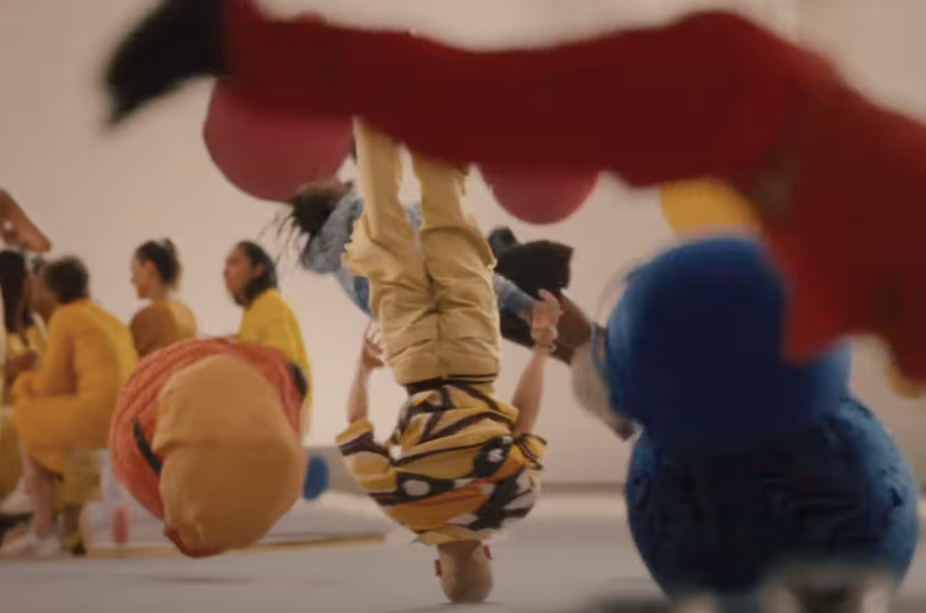 People in monochromatic outfits of all colors dance with props