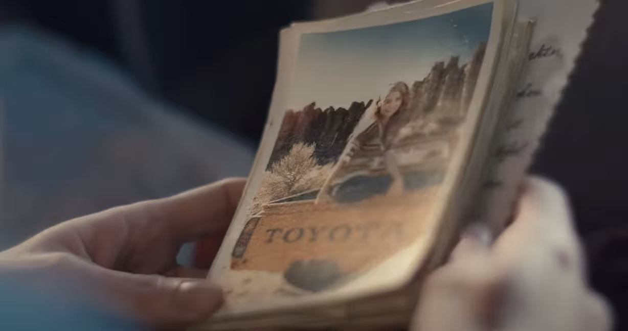 A person holds a stack of film photos showing a young woman and her dog on adventures