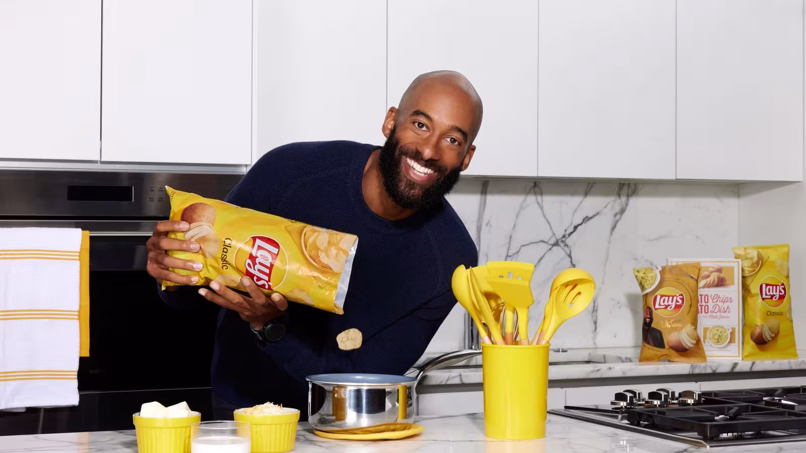 Matt James pours a bag of Lays potato chips into a sauce pot