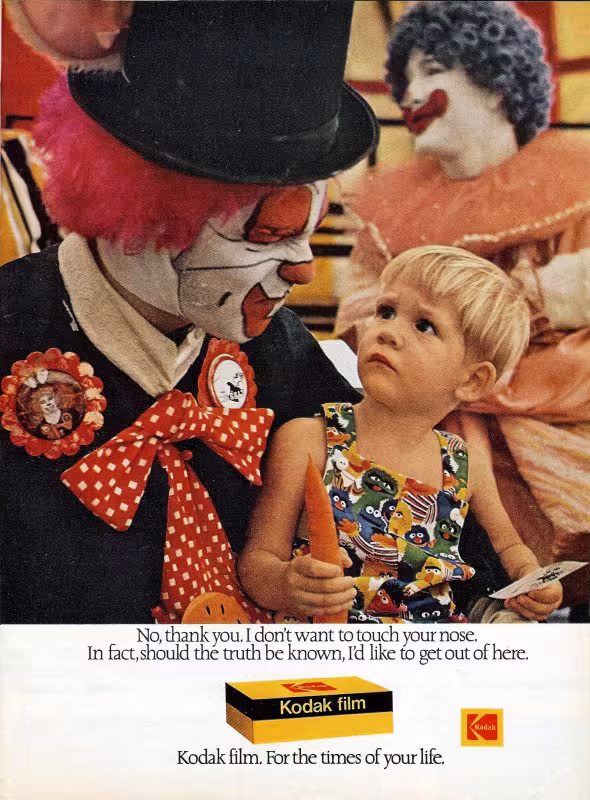A child looks horrified in the lap of a clown